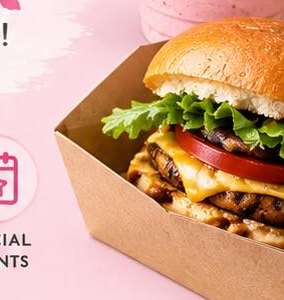 A cheeseburger with lettuce and tomato in a cardboard tray